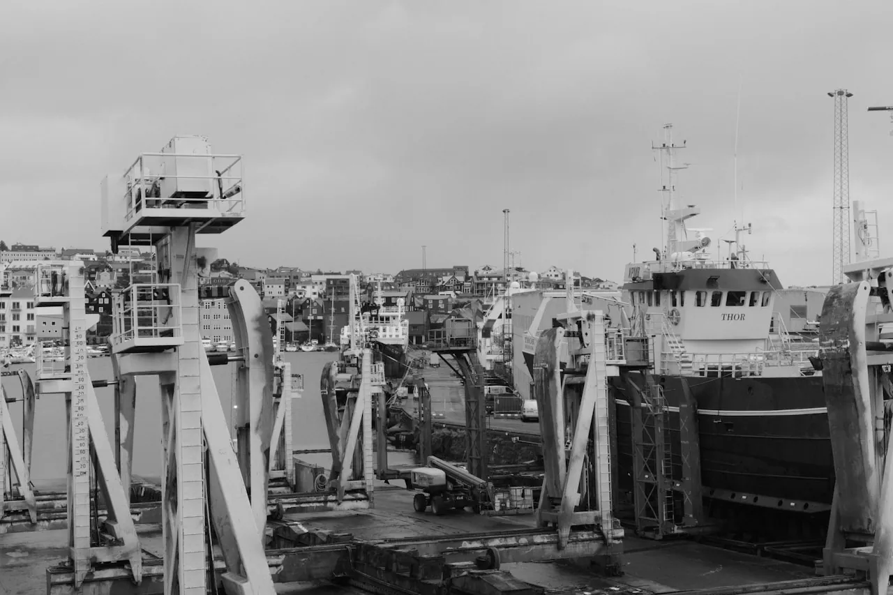Weathered industrial Gulf Coast port town with cranes, docks and working boats under overcast sky